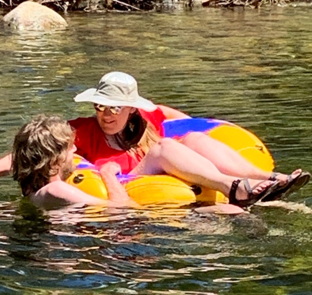 My daughter in an inflatable ring in the Merced river with her boyfriend swimming next to her