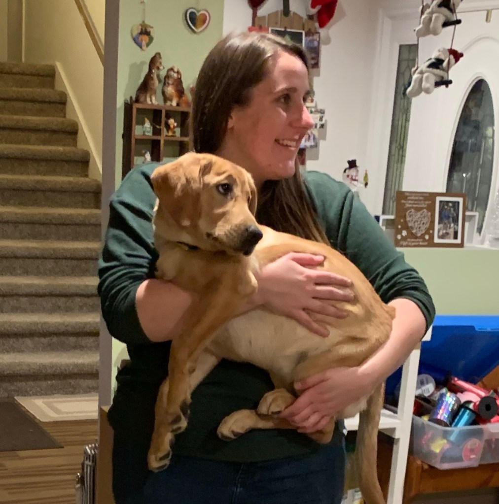 Blondie standing holding the dog. 