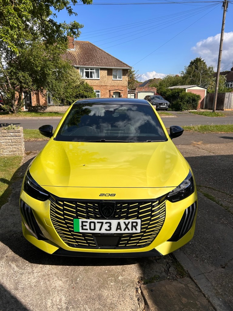 The front of a Peugeot 208, bright yellowish green.